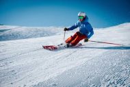 Skifahrer mit Ausrüstung fährt Berg hinunter