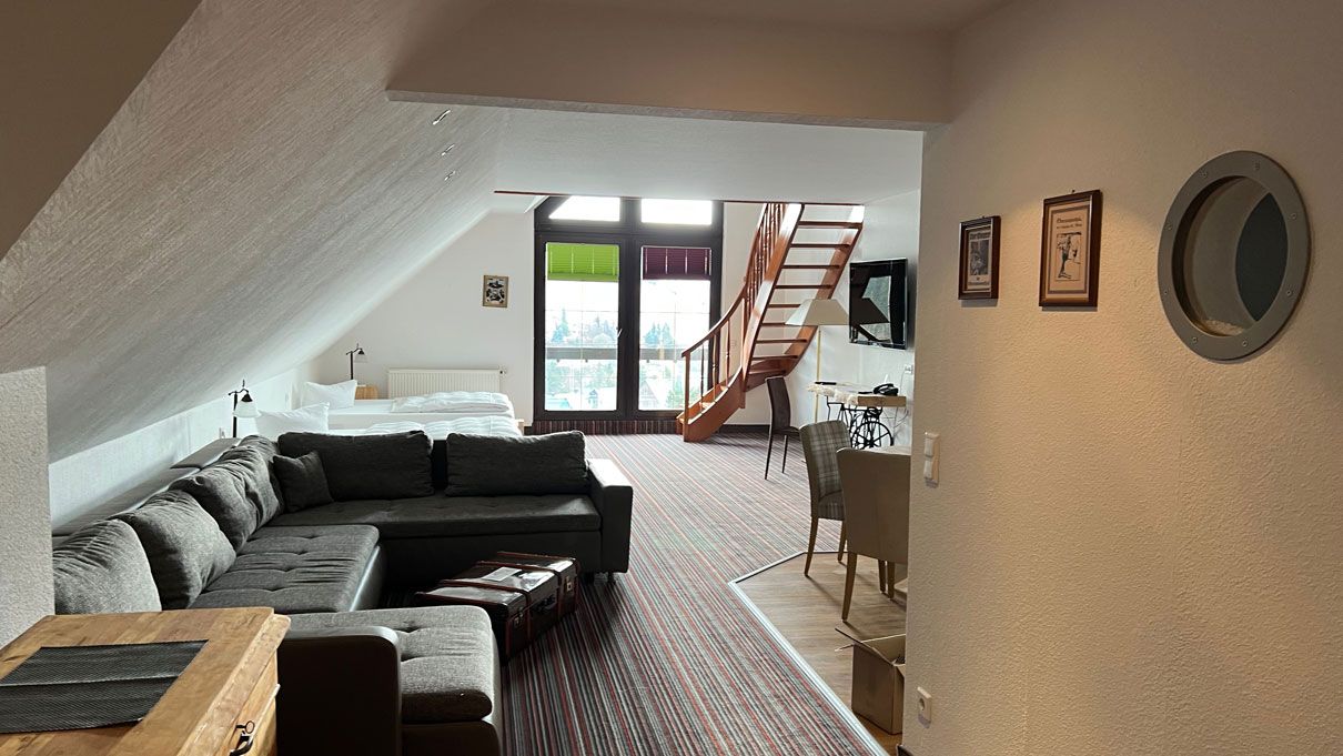 Gesamtansicht Zimmer mit Couch und Treppenaufgang