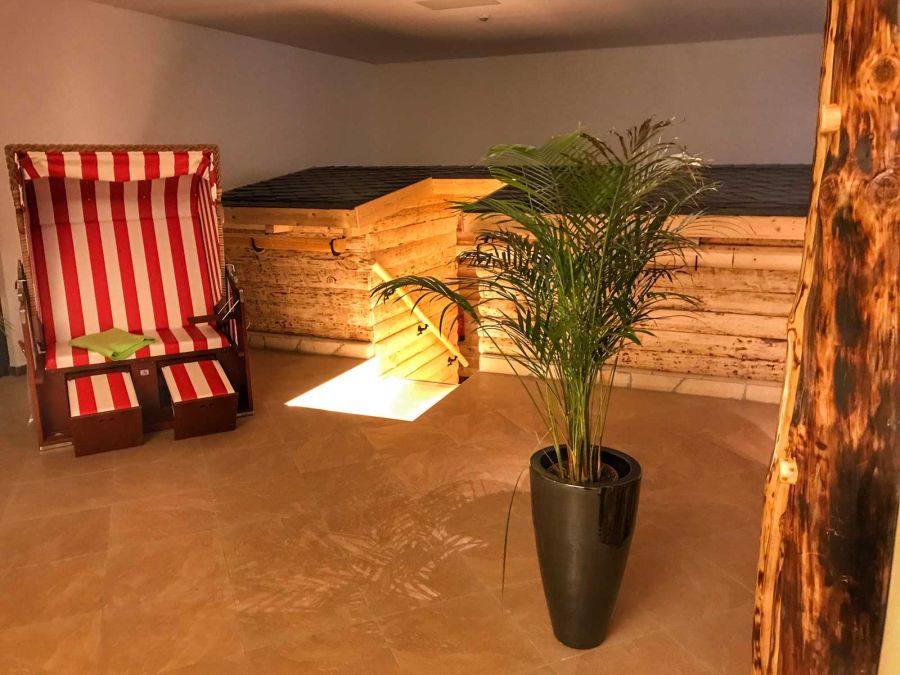 Eingang Holzsauna mit Strandkorb und Pflanze