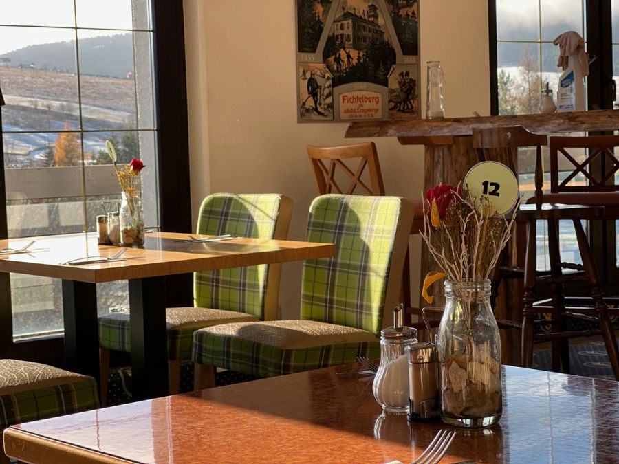Restaurant Detailaufnahme mit Blumenstrauß und grünen Stühlen